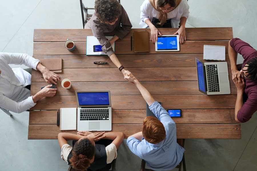 Group of colleagues sitting around a desk with their laptops